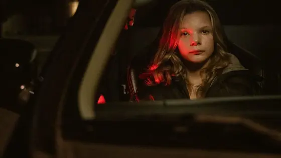 Girl sitting in a car in the dark.