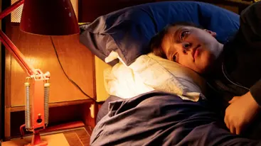 Photo of a teenager lying awake in bed.