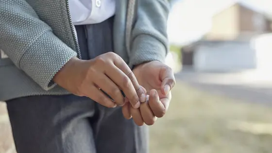 A young person's hands picking at their nails