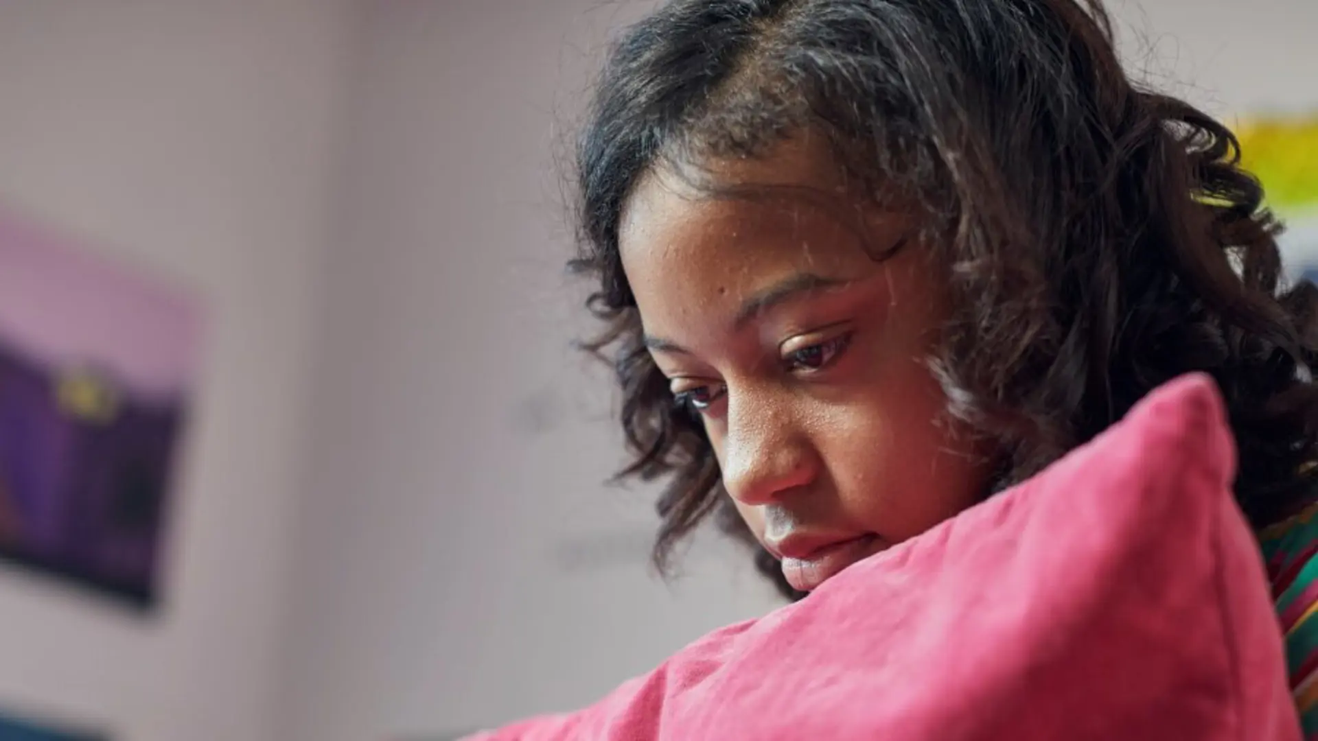Girl feeling sad while alone and holding a pillow.