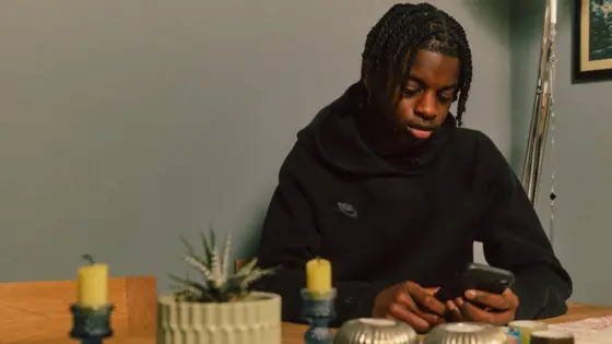 Photograph of a teenager using their mobile phone indoors.