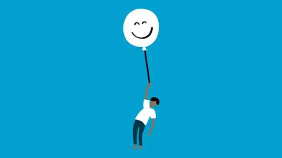 Boy holding a smiley face balloon