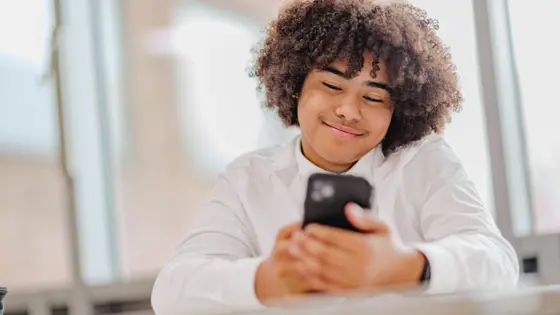 Teenager looking at their phone while smiling.