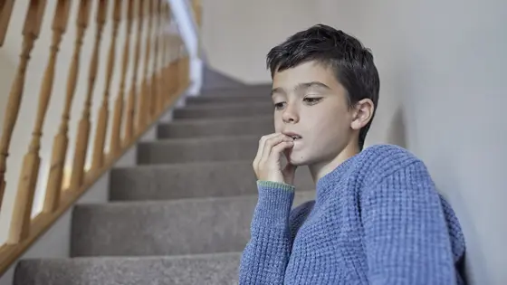 Young boy sat on the stairs looking anxious