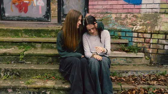 Two teenage girls sat outside comforting each other