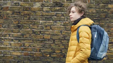 Photo of a teenager walking in front of a wall