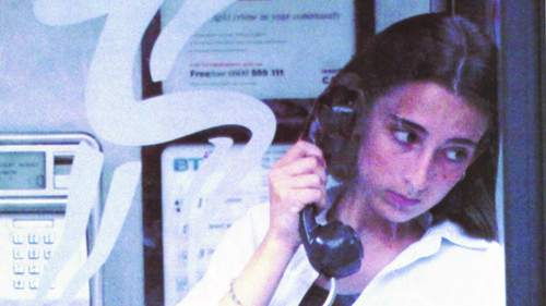 A child making a phone call from a phone box