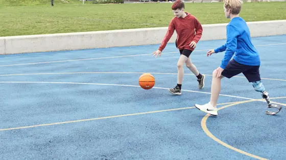Photo of two young people playing basketball.