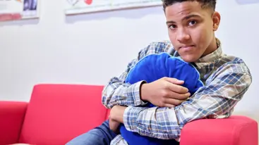 A young person hugging a cushion