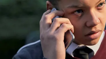 Teenager in school uniform speaking on the phone.