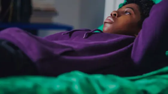 Photograph of a young child lying on their bed.