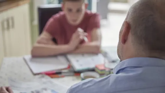 Teenage boy doing homework with carer.