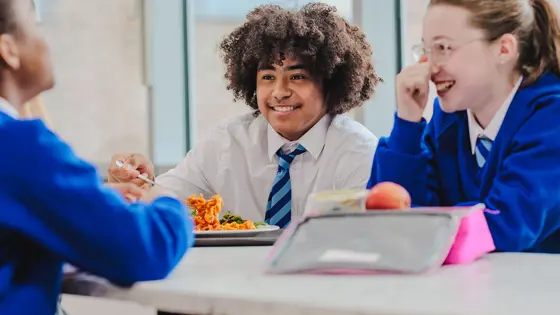 A school girl and school boy sat next to each other at a lunch table