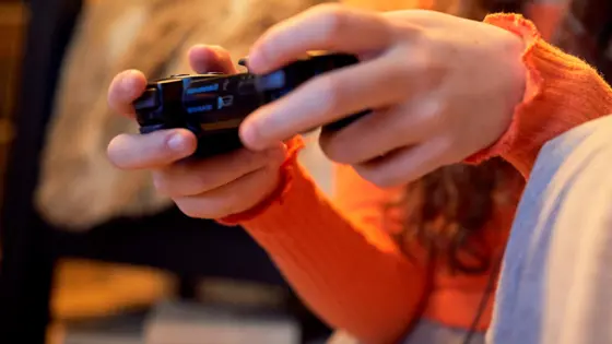 Photo of a close up of a young person's hands holding a controller.
