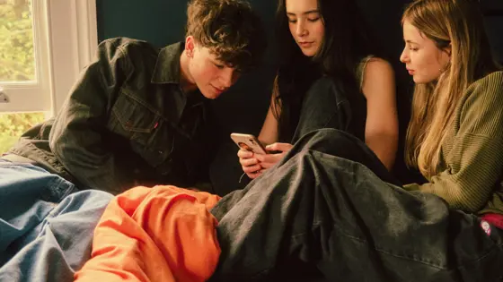 Photograph of three young people looking at a mobile phone.