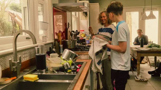 Photograph of a young person and adult washing dishes together.