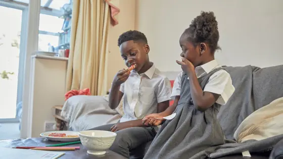 Two children sat in a living room, eating toast.