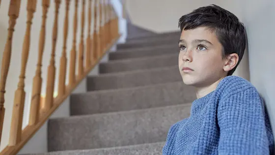 A child sitting on a staircase and looking into the distance