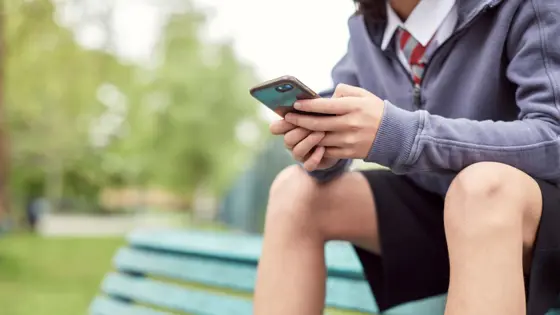 A child sat on a bench, using their mobile phone.