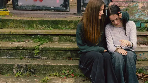 Two teenage girls sat outside comforting each other