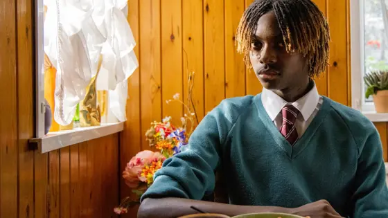 Photo of a boy sitting in school uniform at home.