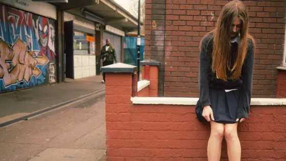 Photograph of a girl leaning against a wall.
