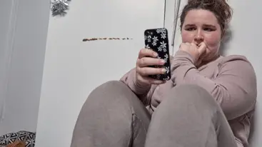 A young person looking at their phone and looking worried