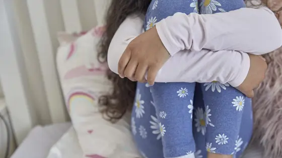 A young girl sat with her arms wrapped around her legs
