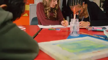 A photograph of three teenagers working at a desk.