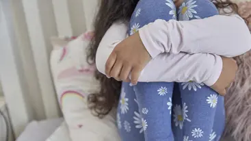 A young girl sat with her arms wrapped around her legs
