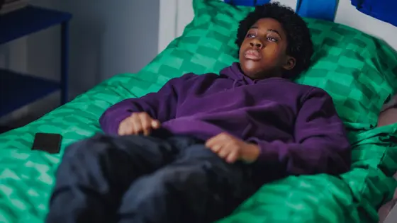 Photo of a teenager lying on a bed staring at the ceiling.
