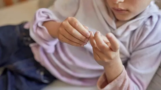 Photo of a young person lying down looking at their hands.
