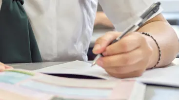 Close up photo of a young person writing in school.