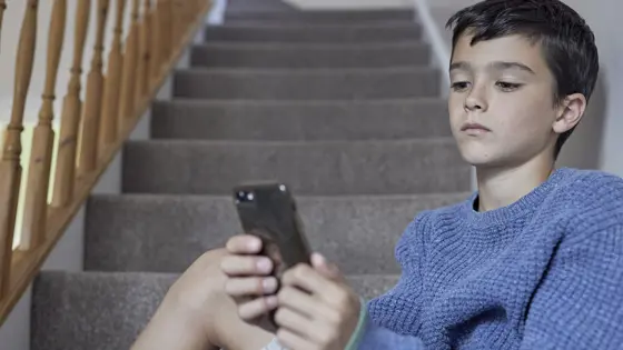 Young boy sat on the stairs looking at his phone