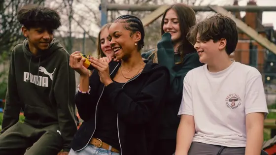 Photograph of a group of young people smiling in a park.