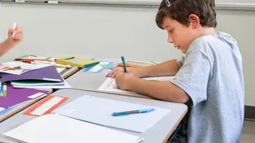 Photo of a child sitting doing schoolwork.