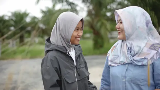 Photo of two teenagers smiling and speaking to each other.