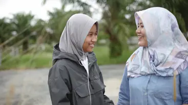 Photo of two teenagers smiling and speaking to each other.