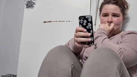 A young person sat on the floor with a phone in their hand