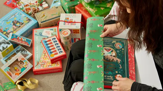 Photograph of a woman wrapping Christmas gifts.