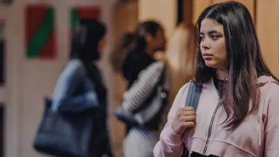 Photograph of a teenager in school with a group of teenagers behind them.