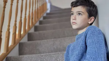 A child sitting on a staircase and looking into the distance